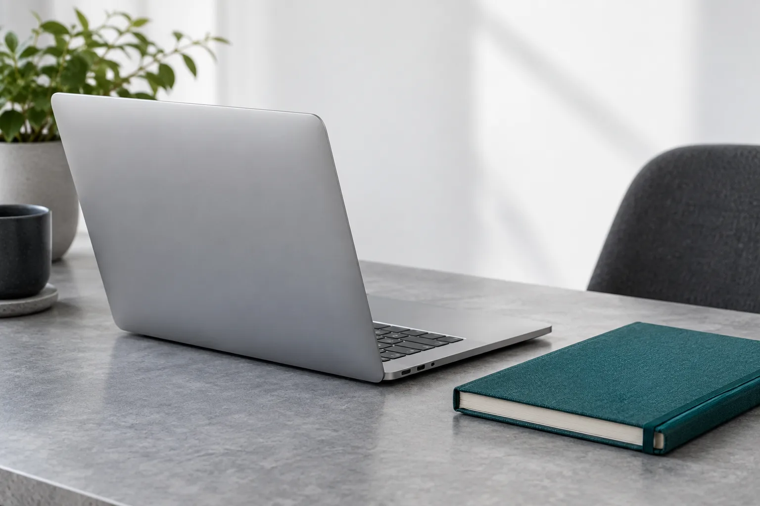 A quiet Mac workspace with a teal notebook, illustrating a local email workflow.